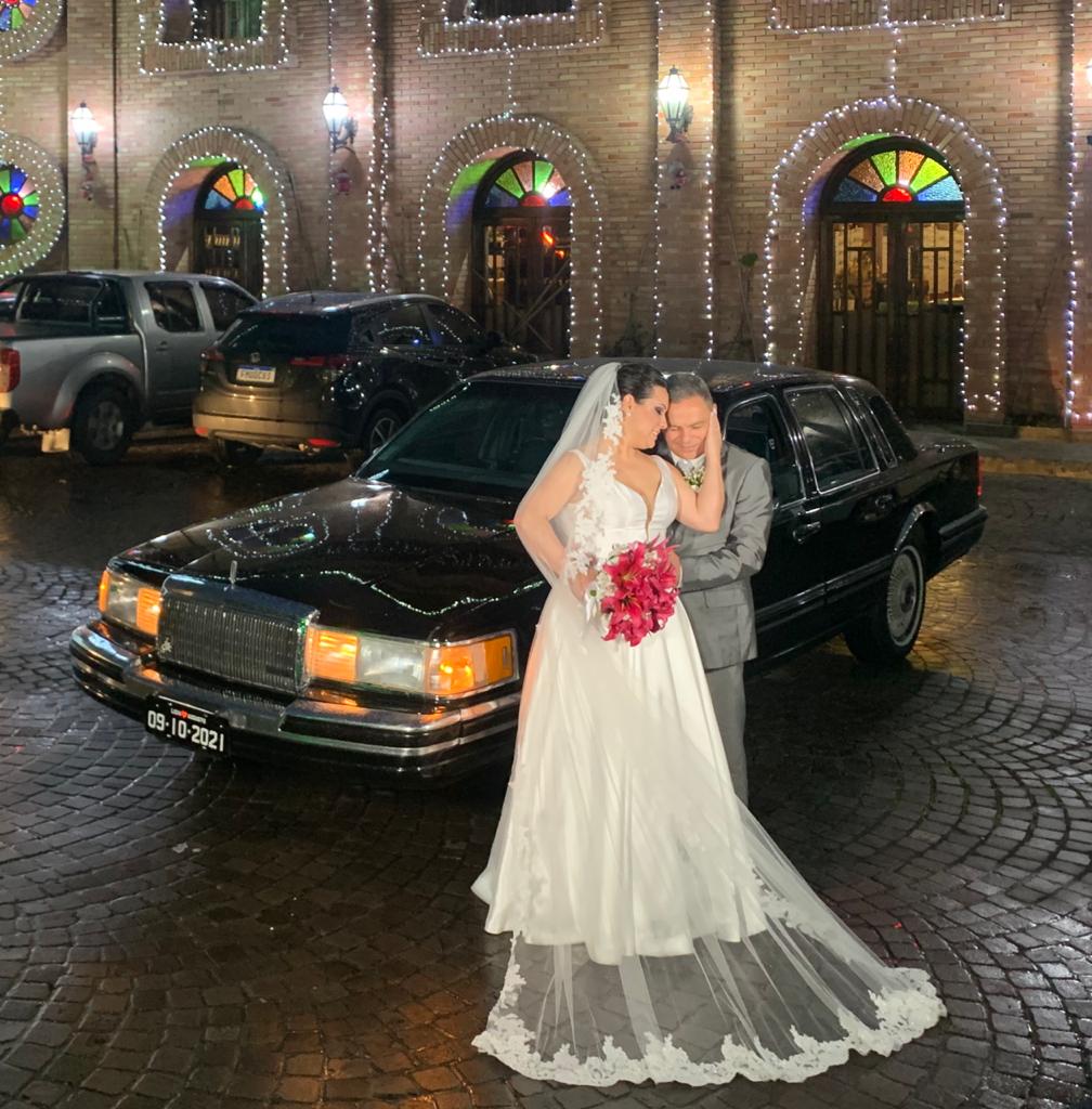 Casal de noivos na frente do Lincoln em Curitiba, com um transporte luxuoso e sofisticado para o grande dia.